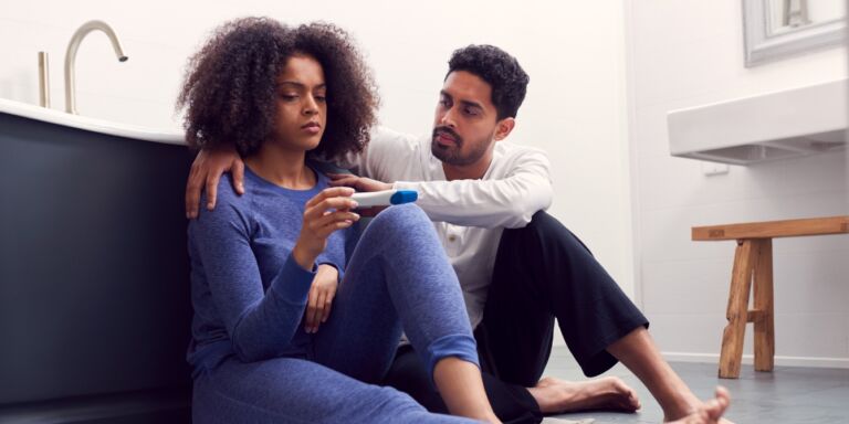 sad woman and man looking at pregnancy test Motherly