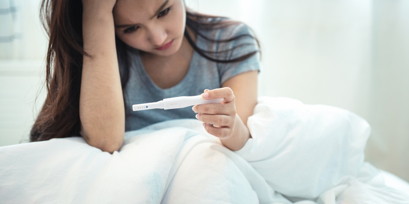 sad woman holding pregnancy test Motherly