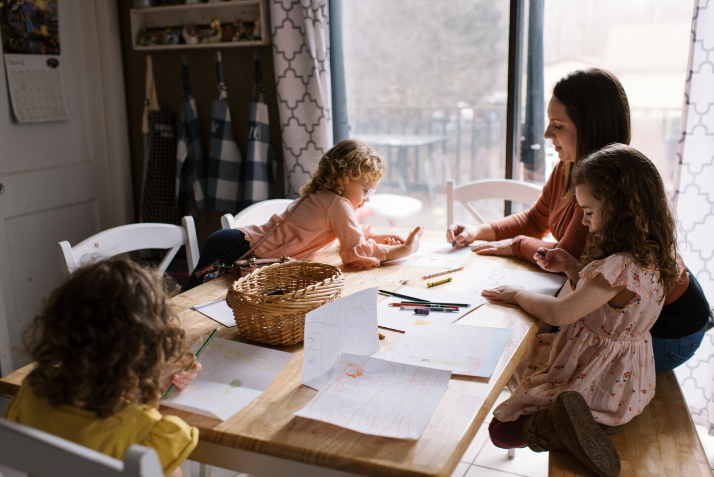 A mother and her three daughters drawing together at the kitchen table.