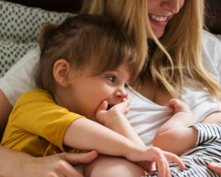 mom nursing a baby holding a toddler Motherly