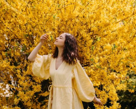 woman in yellow dress by forsythia flowers Motherly