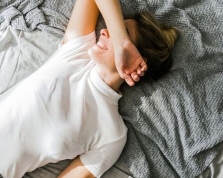 woman on bed smiling covering her face Motherly
