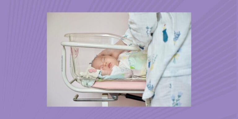 Newborn baby girl laying in clear cradle at the hospital while mom stands beside it and checks on her