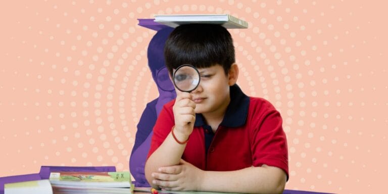 Kid sitting at desk being silly with book on his head and using a magnifying glass to look at the camera