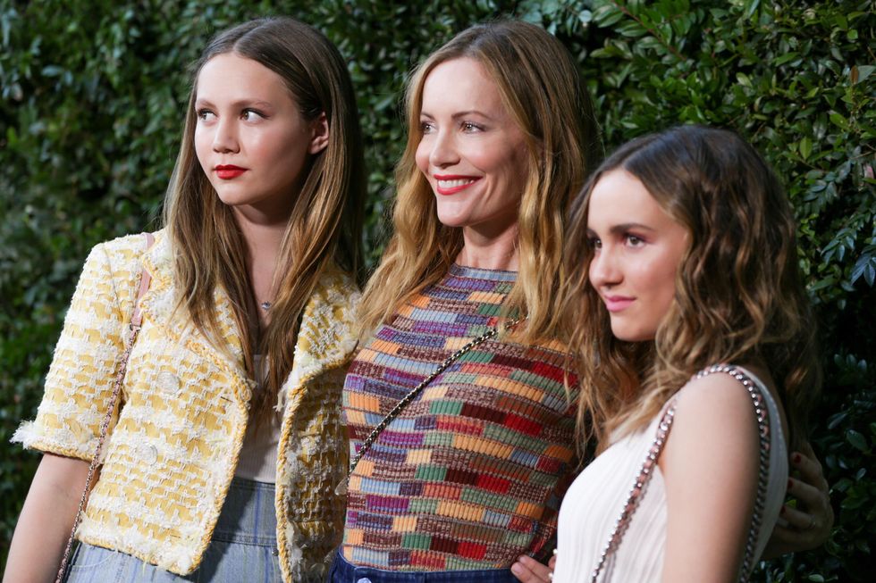 leslie-mann-and-her-two-daughters-on-a-red-carpet-with-faux-greenery-backdrop