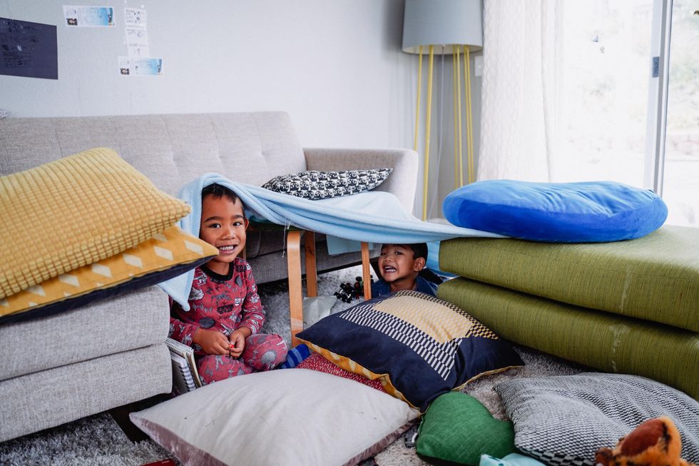 toddlers building fort in living room